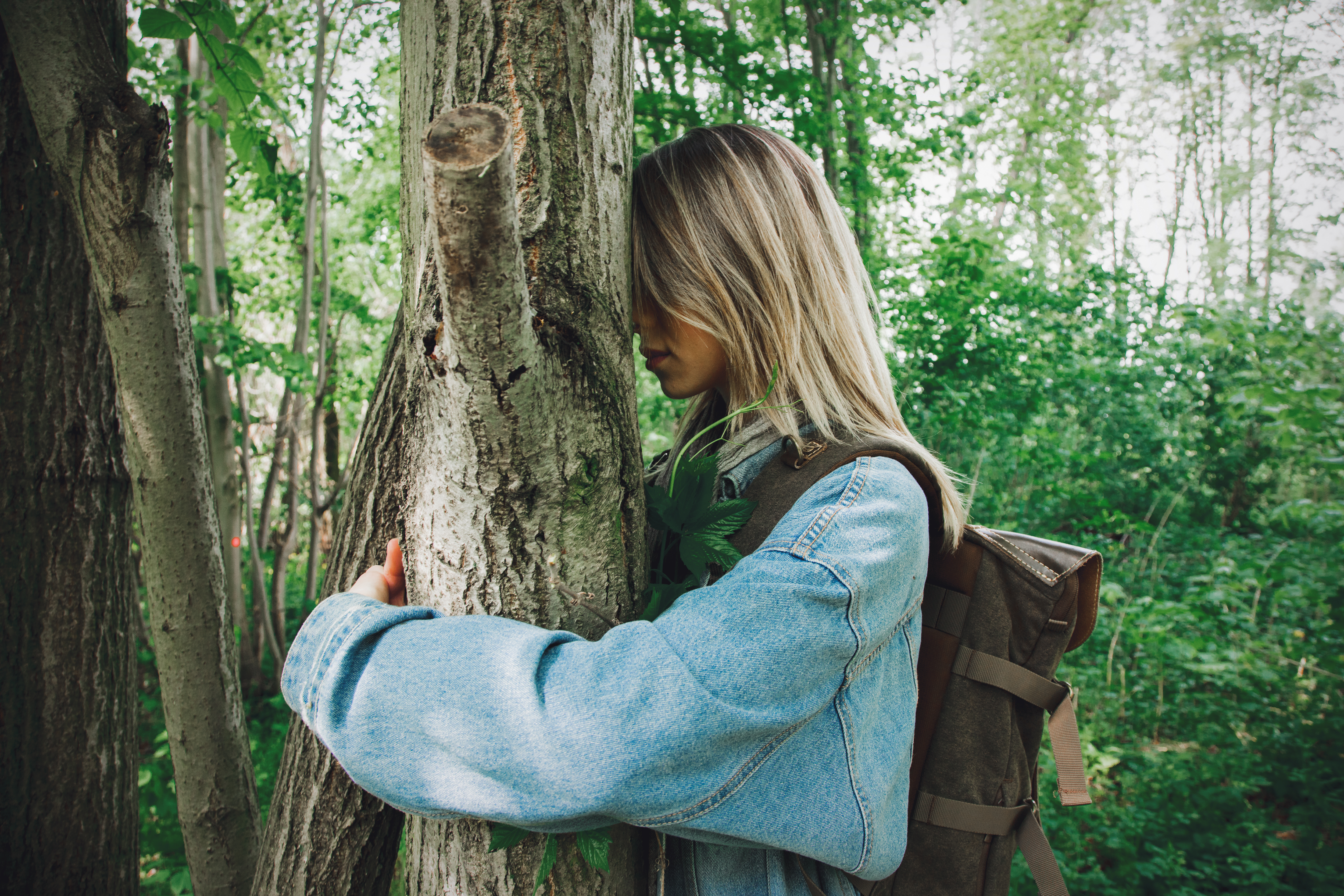 Woman-with-backpack-hugging-a-tree-in-forest-2022-01-12-17-03-22-utc